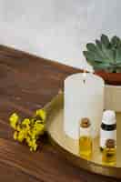 Foto grátis limonium flor com vela acesa grande branca e garrafa de óleo essencial na mesa de madeira