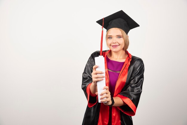 Linda aluna em vestido segurando diploma.