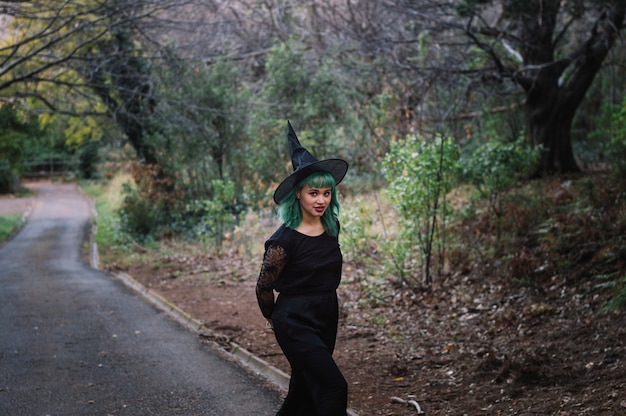 Linda bruxa andando pela estrada da floresta