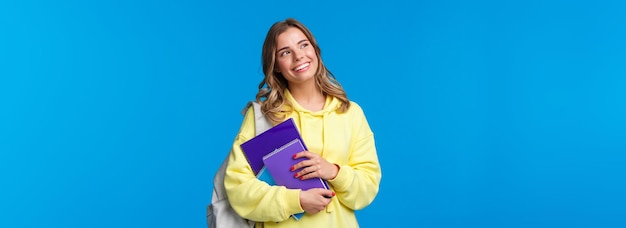 Foto grátis linda e bonita loira sonhadora estudando na faculdade segurando mochila e cadernos em casa