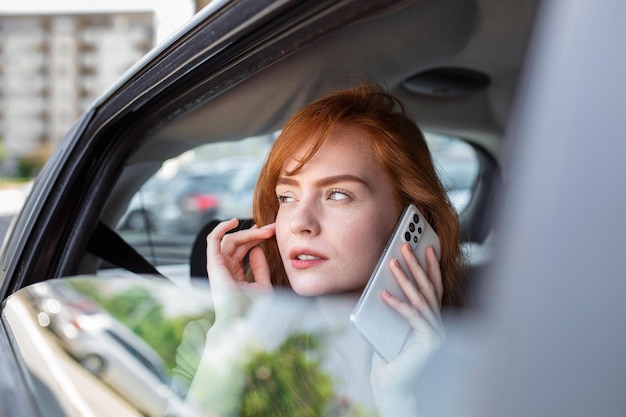 Linda empresária está se deslocando do escritório no banco traseiro de seu passageiro de empresário de carro de luxo viajando em um táxi de transferência na rua urbana da cidade