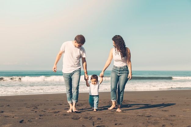 Linda família caminhando ao longo da praia