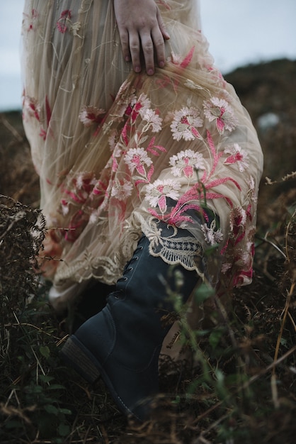 Linda foto vertical de uma mulher em um vestido rosa claro e botas pretas