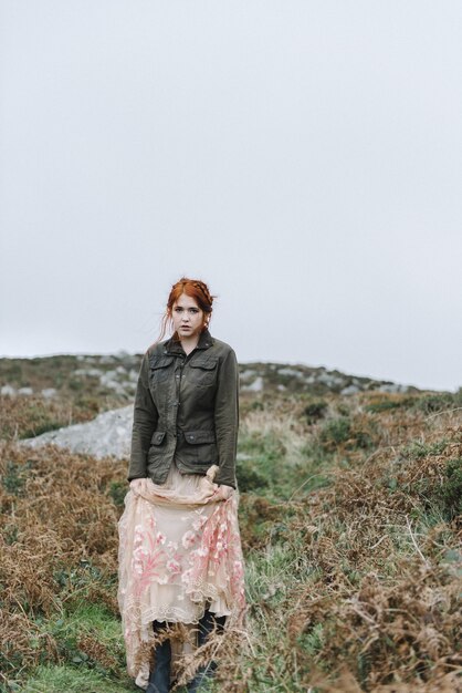 Linda foto vertical de uma mulher ruiva com pele totalmente branca em um atraente vestido claro