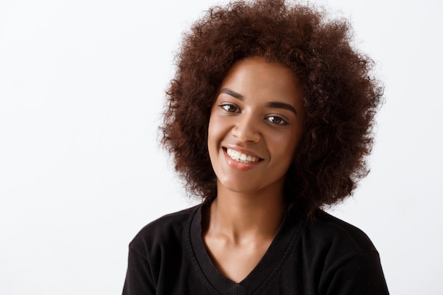 Linda garota africana sorrindo sobre parede de luz.