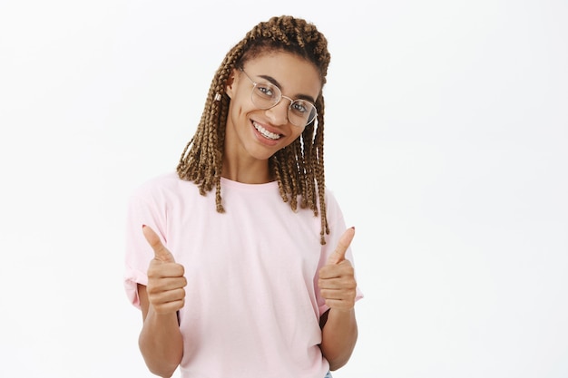 Linda garota afro-americana atrevida mostrando o polegar para cima em aprovação, elogie a boa escolha, parabéns ou elogie você