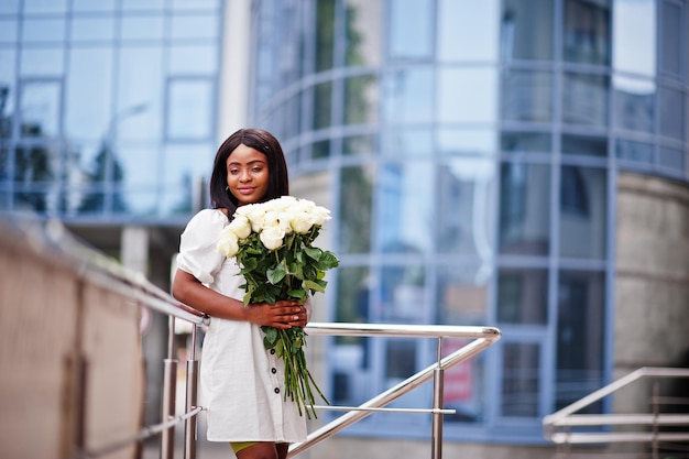 Linda garota afro-americana segurando buquê de flores de rosas brancas em namoro na cidade empresária negra com buquê de flores