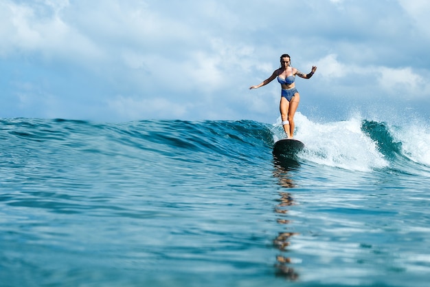 linda garota andando em uma prancha de surf nas ondas