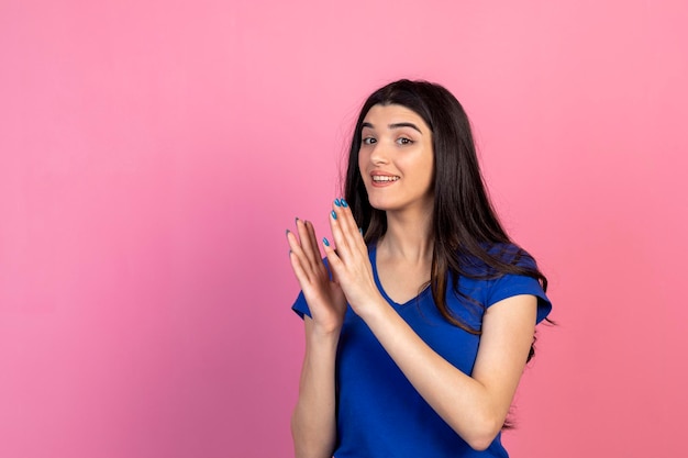 Linda garota batendo palmas e ficar no fundo rosa Foto de alta qualidade