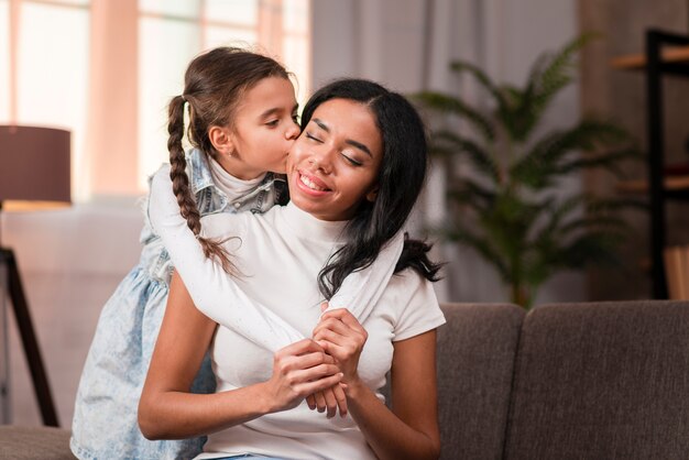 Linda garota beijando sua mãe na bochecha