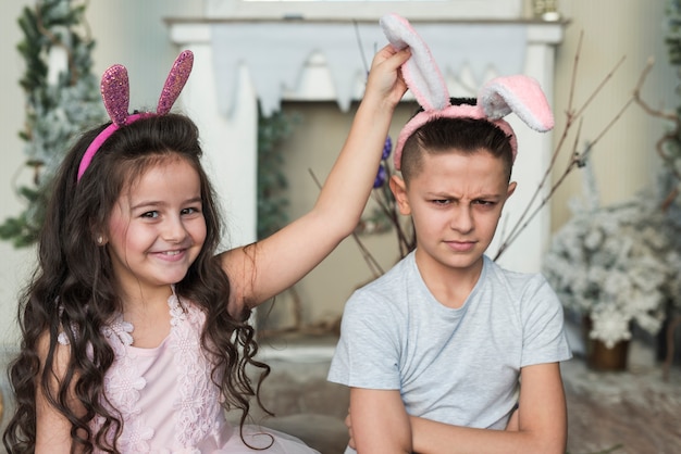 Linda garota com garoto ofendido em orelhas de coelho