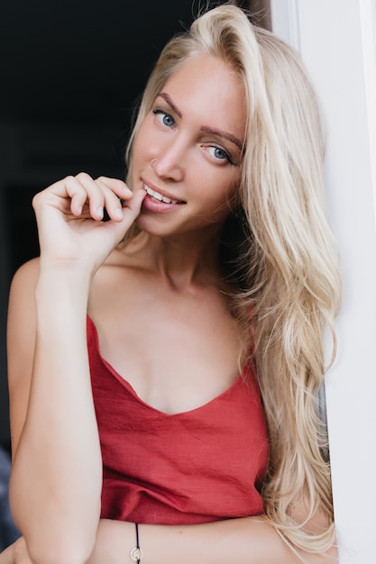 Linda garota com longos cabelos loiros posando divertidamente em uma camisola de seda. modelo feminina de pijama