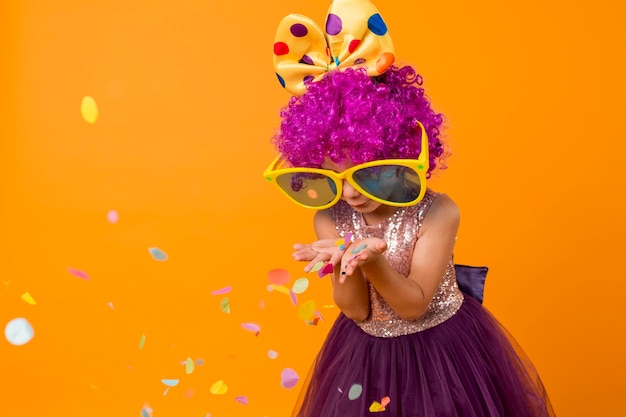 Foto grátis linda garota com peruca de palhaço soprando confete