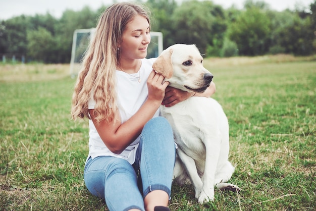 linda garota com um lindo cachorro em um parque na grama verde.