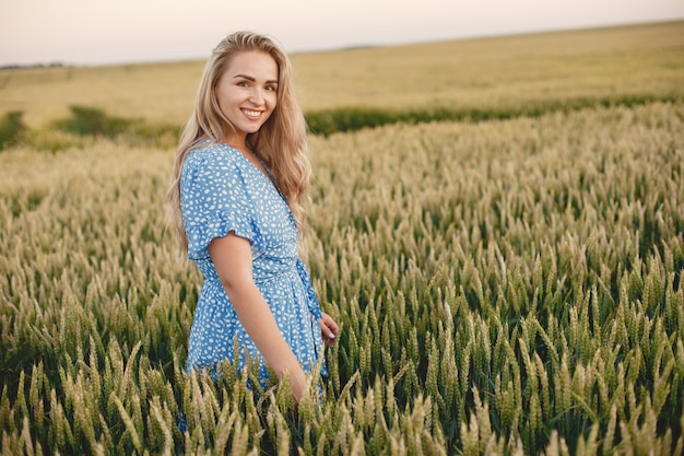 Linda garota com um vestido azul. Mulher em um campo de verão.