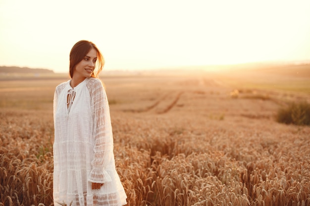 Linda garota com um vestido branco. Mulher em um campo de trigo de outono.