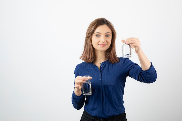 Linda garota de blusa azul, segurando um copo de água branco.