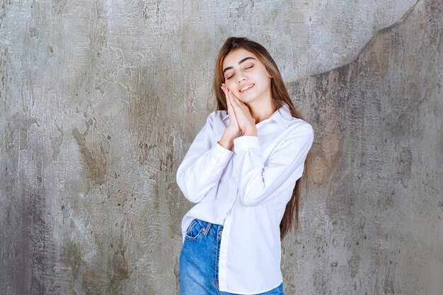 Linda garota de cabelo comprido com blusa branca em pé e dormindo