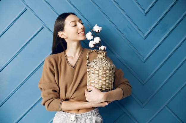 Linda garota de pé em um estúdio com flores de algodão