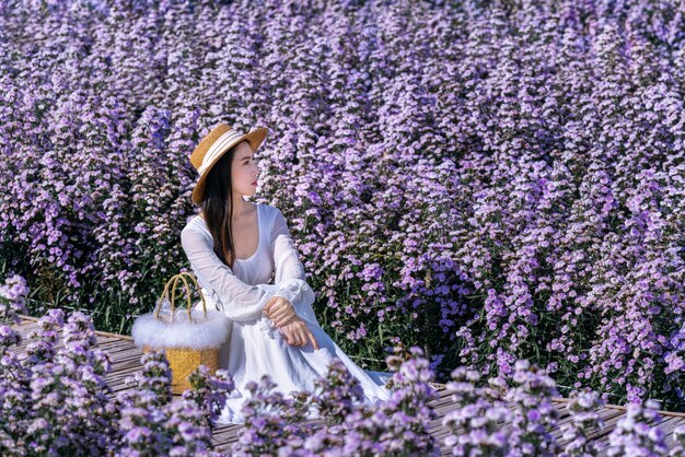 Linda garota de vestido branco sentada em um campo de flores de Margaret