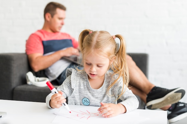 Foto grátis linda garota desenhando esboço com marcador em casa