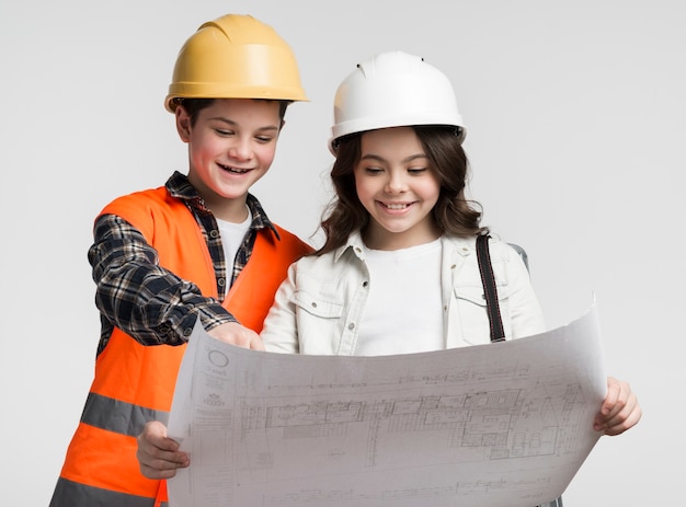 Linda garota e menino lendo o plano de construção