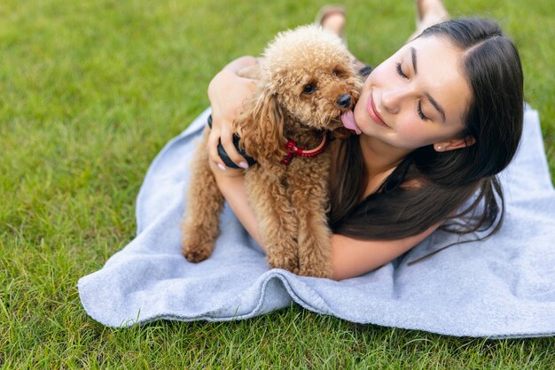 Linda garota e seu cachorrinho poodle dourado de estimação passeando em um parque público ao ar livre