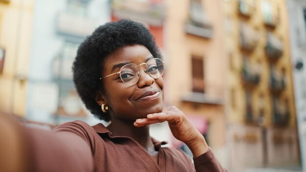 Linda garota encaracolada afro-americana parecendo fofa tomando selfie