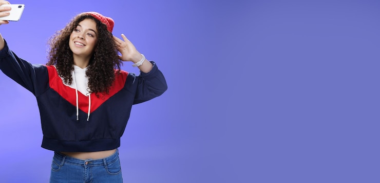 Foto grátis linda garota fazendo selfie para memorizar a viagem em pé no gorro de inverno quente e moletom posando como pul