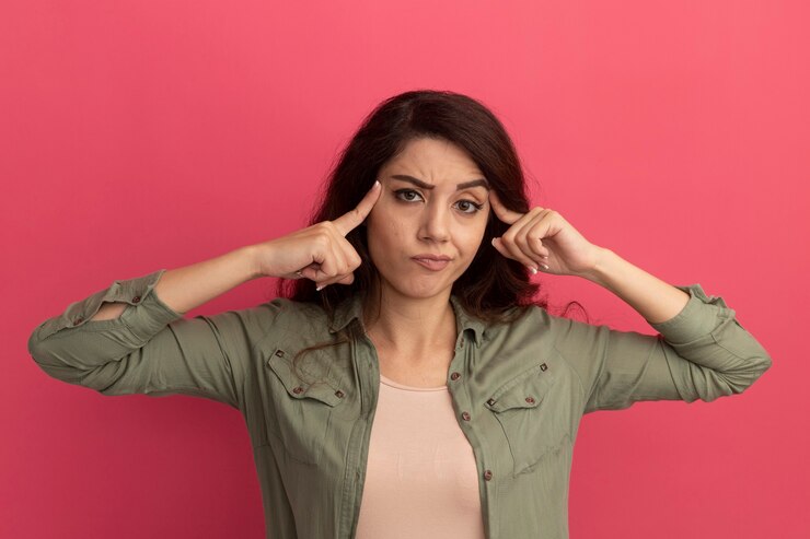 Foto grátis linda garota impressionada vestindo uma camiseta verde oliva e colocando os dedos na têmpora isolada na parede rosa