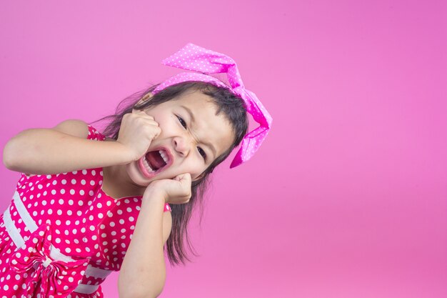 Linda garota jovem vestindo uma camisa listrada vermelha, amarrou um laço rosa na cabeça e rosa.