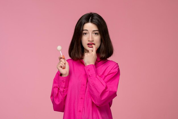Linda garota linda jovem morena de camisa rosa com batom vermelho mordendo o dedo