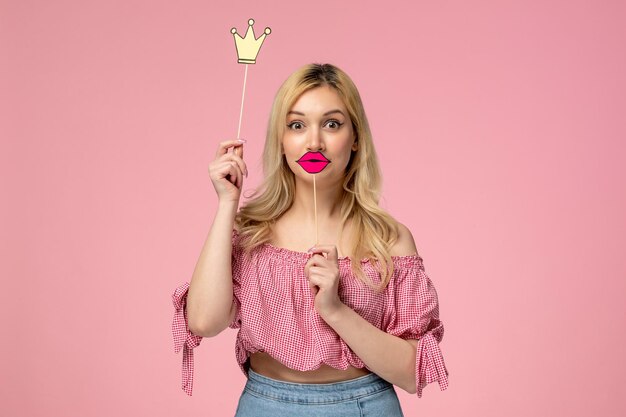 Linda garota loira usando batom vermelho na blusa rosa com coroa e lábios de requisitos