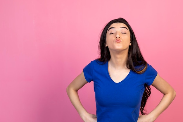 Linda garota mandando beijo para a câmera no fundo rosa Foto de alta qualidade