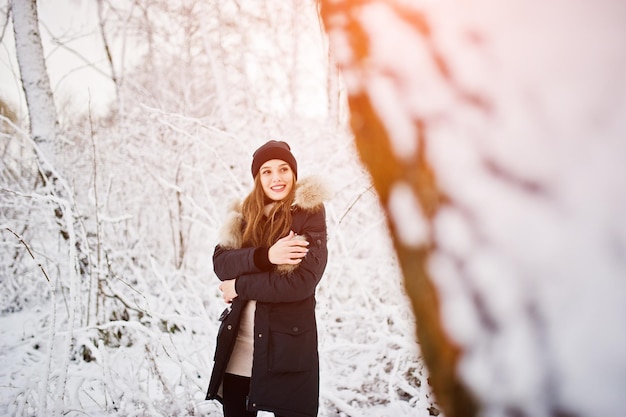 Linda garota morena em roupas quentes de inverno modelo na jaqueta de inverno e chapéu preto