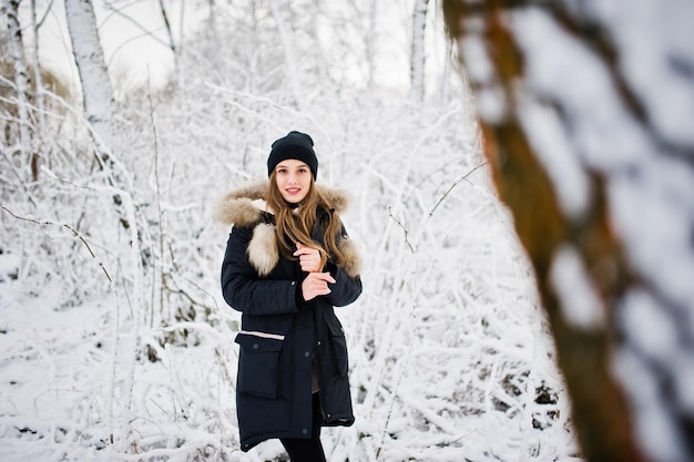 Linda garota morena em roupas quentes de inverno Modelo na jaqueta de inverno e chapéu preto