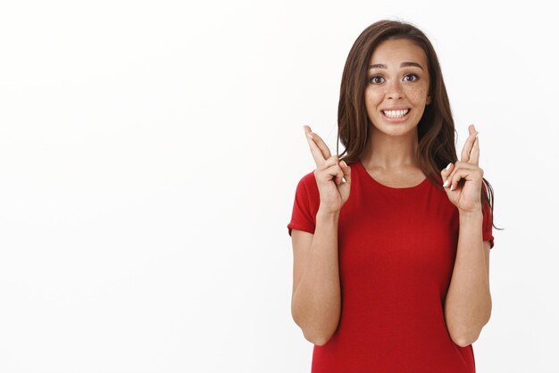 Linda garota morena nervosa com sardas sorrindo esperançoso acredite que os sonhos se realizam cruzar os dedos boa sorte suplicando antecipando milagre esperando fielmente resultados importantes