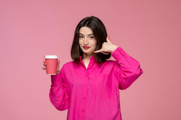 Linda garota muito adorável na camisa rosa com batom vermelho fazendo sinal de telefonema