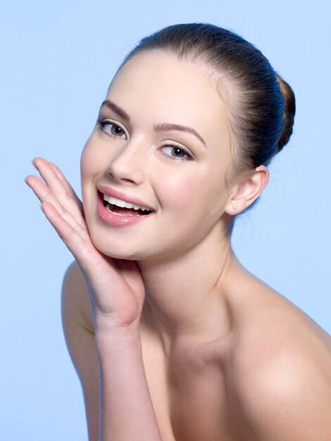 Foto grátis linda garota rindo com as mãos no rosto azul