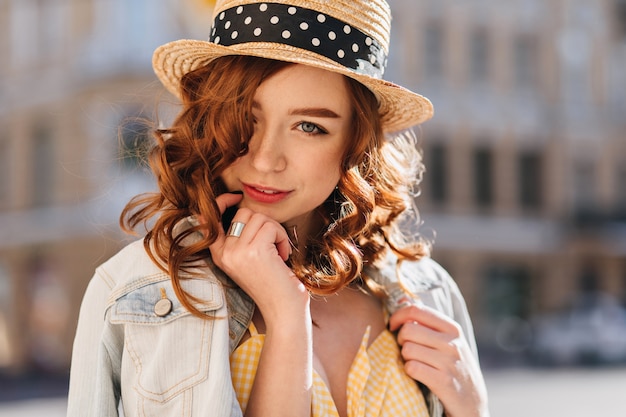 Linda garota ruiva de olhos azuis posando em blur city. Foto ao ar livre de uma jovem ruiva deslumbrante em uma jaqueta da moda.