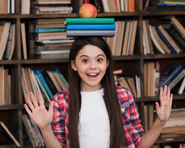 Foto grátis linda garota segurando livros na cabeça