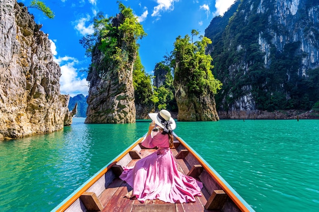 Linda garota sentada no barco e olhando para as montanhas na barragem de Ratchaprapha no Parque Nacional Khao Sok, província de Surat Thani, Tailândia.