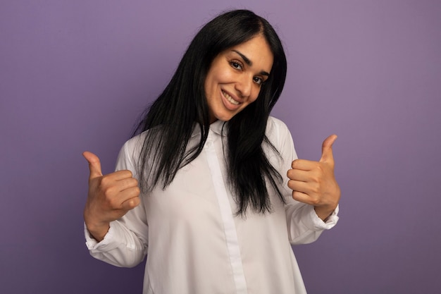 Linda garota sorridente com camiseta branca mostrando os polegares isolados no roxo