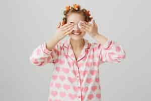 Foto grátis linda garota tirando a maquiagem antes de dormir com almofada de algodão, usando rolinhos de cabelo e pijama