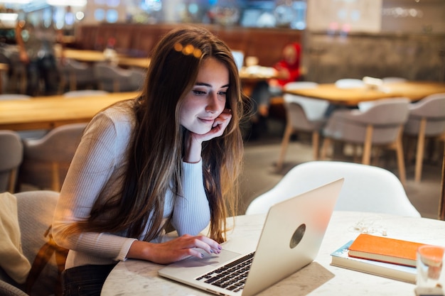 Foto grátis linda garota trabalhando no laptop em um café moderno