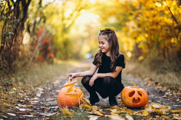 Linda garota vestida em traje de halloween ao ar livre com abóboras