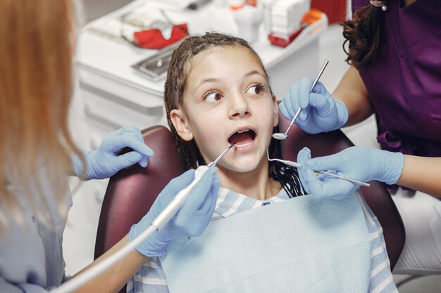 Linda garotinha sentada no consultório do dentista