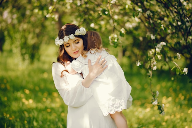 linda jovem grávida em um vestido longo branco com a menina em seus braços