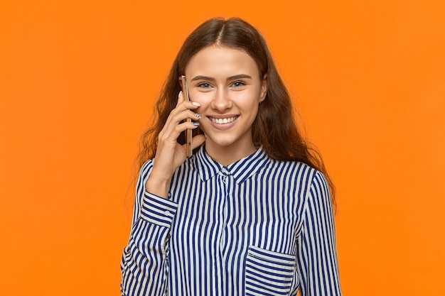 Linda jovem mulher segurando o celular na orelha e sorrindo alegremente, conversando com o namorado