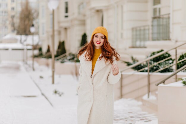 Linda jovem posando com um sorriso em janeiro. Retrato de inverno da garota ruiva rindo.
